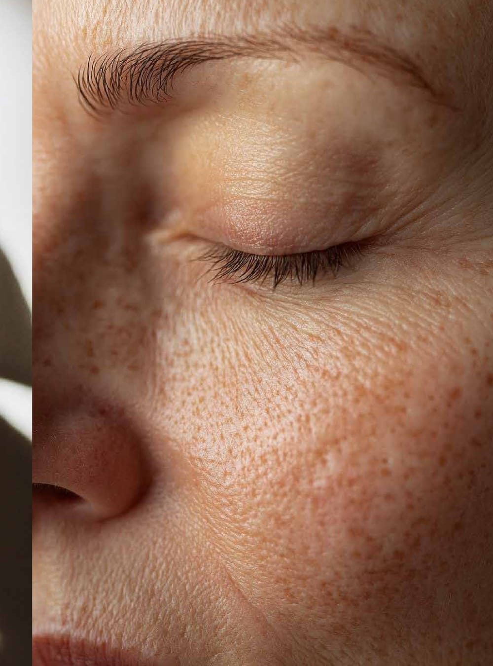 Rostro sereno de una mujer con pecas y los ojos cerrados